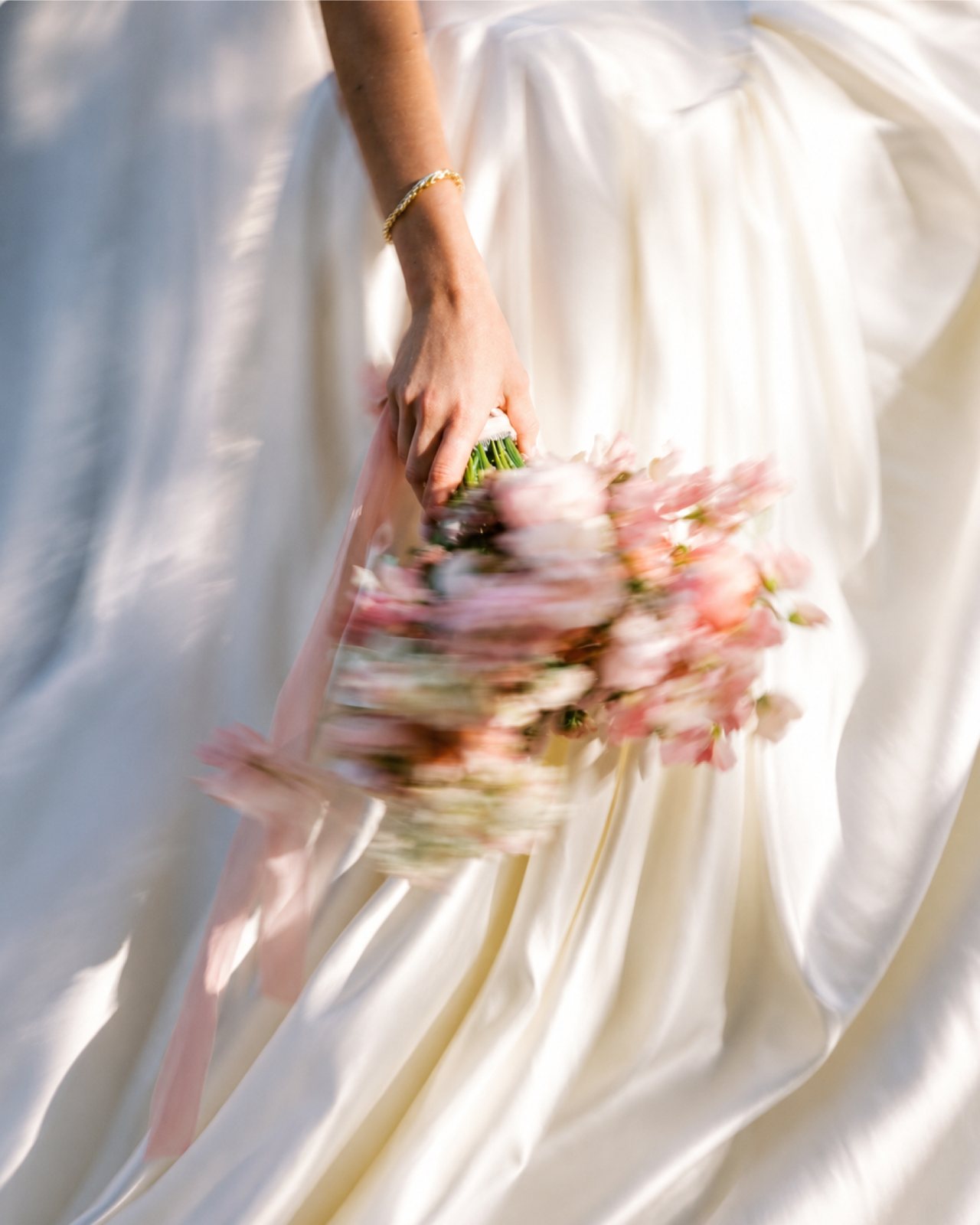 Bride carrying a soft pink bouquet in the sunlight